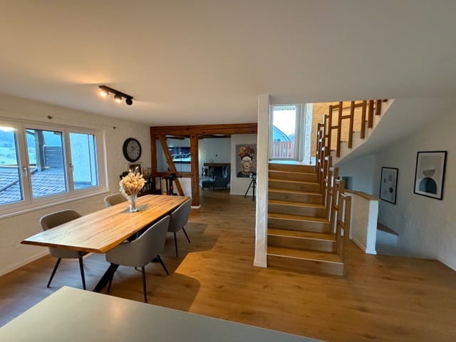 Dining room: Wooden table and chairs, staircase, glass windows, wooden floors