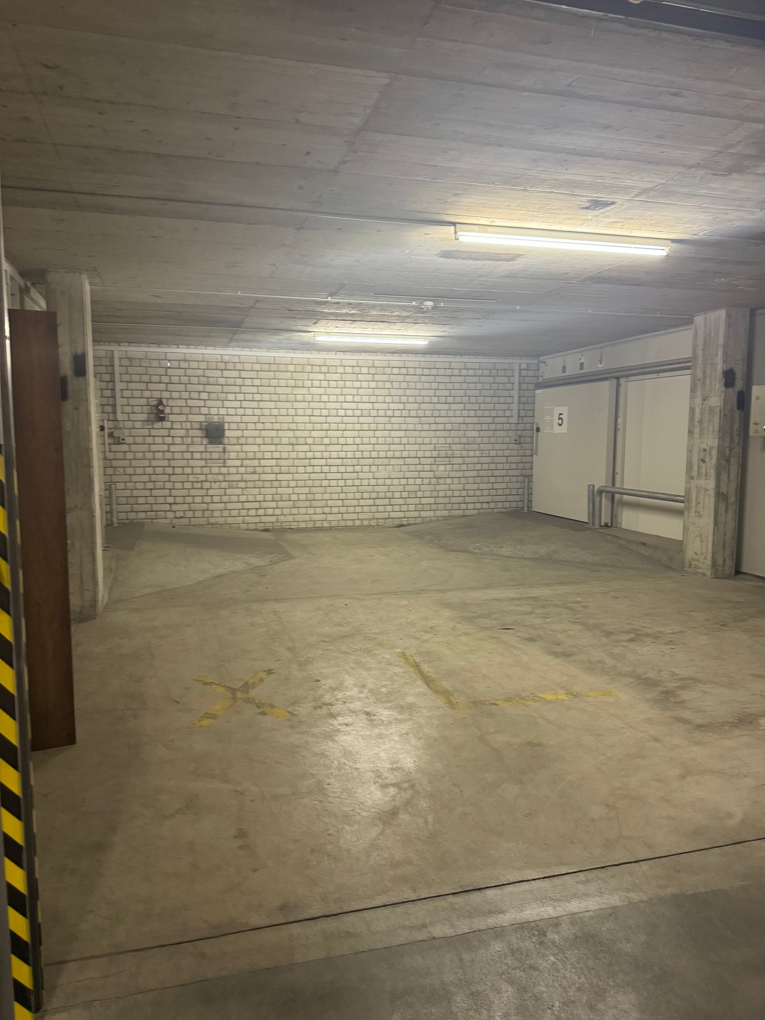 Empty parking lot with white brick wall, yellow lines, and parking bays marked
