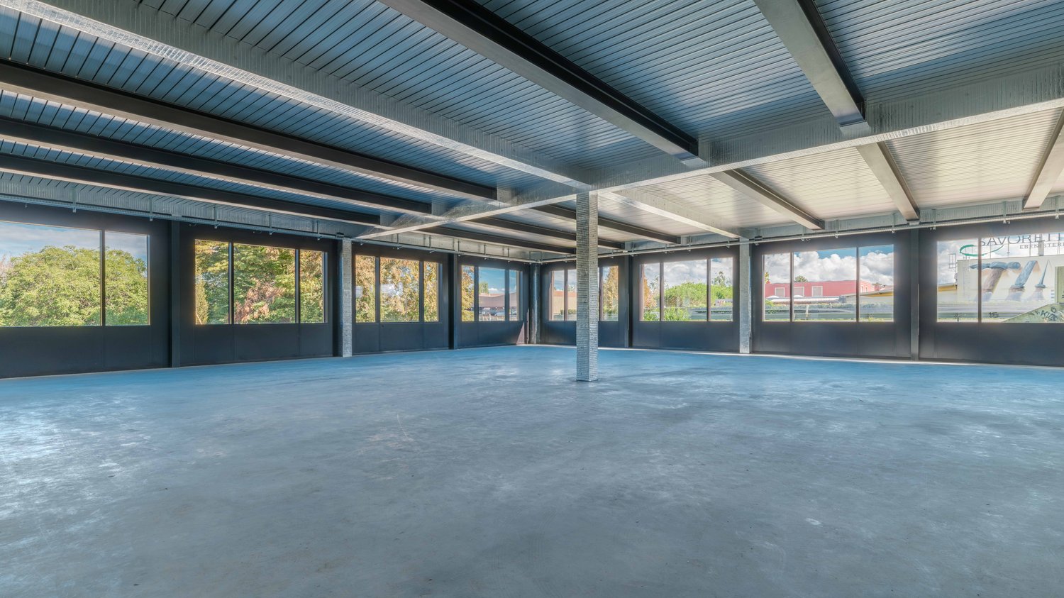 Empty room with metal ceiling, large windows, and concrete floor